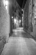 Black and white photo of the beautiful, old, narrow street of Italy, with lights