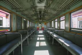 Interior of the train with seats, on the rail among the buildings, in sunlight