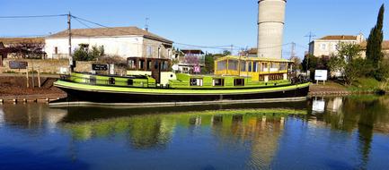 Colorful boat with reflection in the channel, among the colorful buildings and plants, under the blue sky