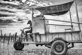 Black and white photo of the man, driving transport, under the sky with clouds