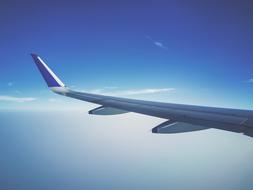 View with the shiny wing of the plane, at background with blue sky with white clouds