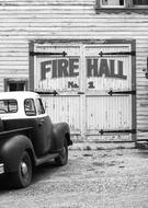 black and white photo of an old car near the fire station