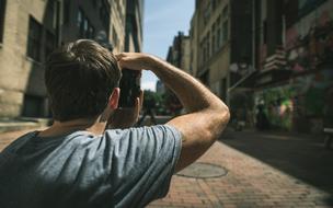 Guy looking on the colorful street with people, in sunlight and shadows