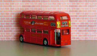 Model of the colorful double decker bus in London, United Kingdom, near the brick wall