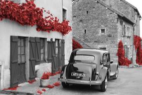 Beautiful, black and white street with the vintage car and red plants in Chateauneuf, Burgundy, France