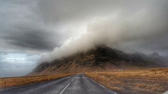 Landscape with the road near the beautiful and colorful mountains in fog, among the fields