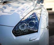 Close-up of the headlight of the beautiful, shiny, grey Nissan GTR