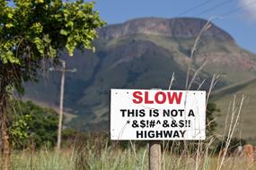 "Slow" sign among the colorful plants near the mountains