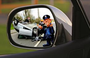 figurine of a policeman in the rearview mirror against the background of an accident