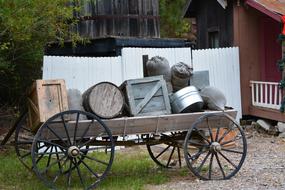 Wagon with wheels and old crates, near the hut, among the plants