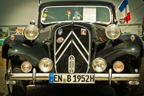 Front of the beautiful, shiny Citroen Traction Avant car, with the flag