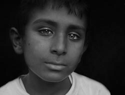 Black and white photo with portrait of the child boy, at black background