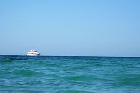 Seascape with boat on the colorful and beautiful water, under the blue sky