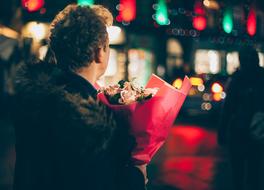 man with a bouquet of flowers on a blurred background at night