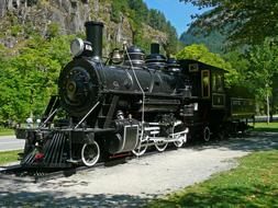 Beautiful landscape with the old locomotive in sunlight, among the mountains with plants