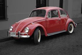 Beautiful, shiny, vintage, red "Volkswagen Beetle" car on the street in black and white colors