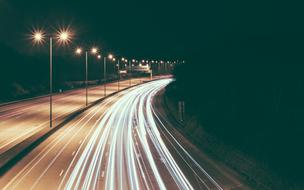 the light of the lanterns of high-speed cars on the highway at night next to the street lamps