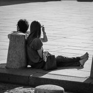 Black and white photo with couple sitting on the pavement, in Paris, France