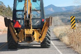 yellow tractor driving on the road along the field