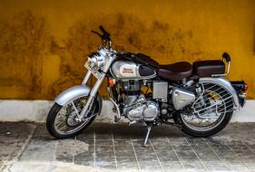 the motorcycle is parked near the building with yellow walls