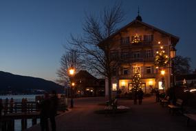 Beautiful landscape with the people, near the town hall in Christmas lights, near the water and mountains, in the evening