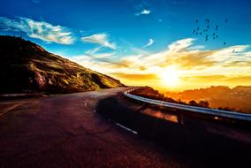 Landscape of the mountain road with fence, at colorful and beautiful sunset among the clouds