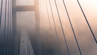 Bridge with ropes, at colorful and beautiful sunset in fog