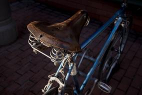 Close-up of the shiny bicycle, with brown leather saddle, among the darkness