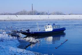 Boat on the beautiful Elbe river, among the snowy shore with plants, in the river