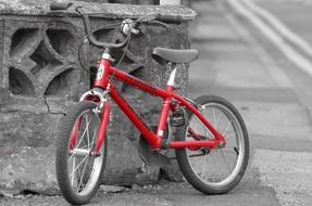 red children's bike stands near the house