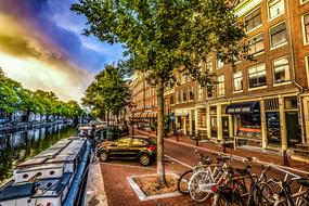 Beautiful landscape of the canal, among the colorful buildings, road, trees, cars and bicycles in Amsterdam, Netherlands