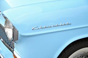 Close-up of the sign, on the beautiful, shiny, vintage, turquoise "Chevrolet" car in sunlight