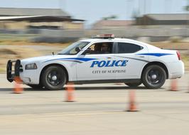 Man driving police car among the traffic cones, outdoors