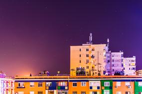 tall houses against the background of a purple sky during sunset