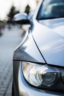 Close-up of the headlight of the shiny "BMW" car on the street