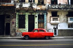 Beautiful view with the vintage, red car on the road, near the old buildings