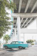 Beautiful, vintage, turquoise car under the bridge, among the plants