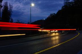 Landscape of the road with car and colorful lighttrail, among the trees, in the evening