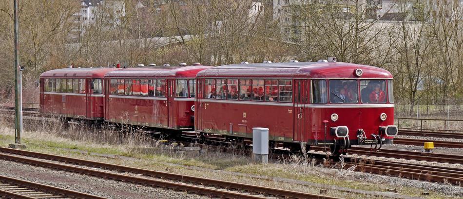 Old, red railbus, with the people, on the railroad, among the plants