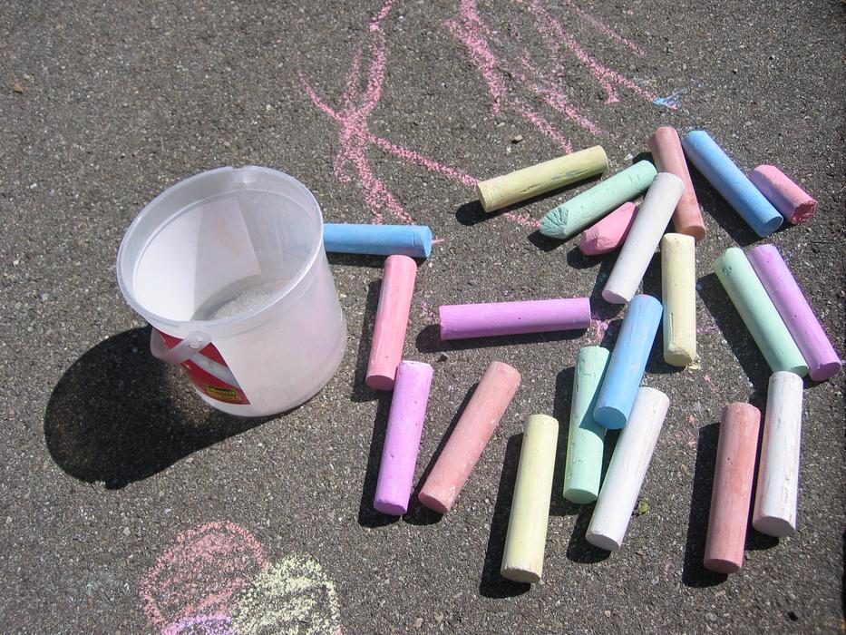 Colorful stick chalks and bucket, on the asphalt in sunlight