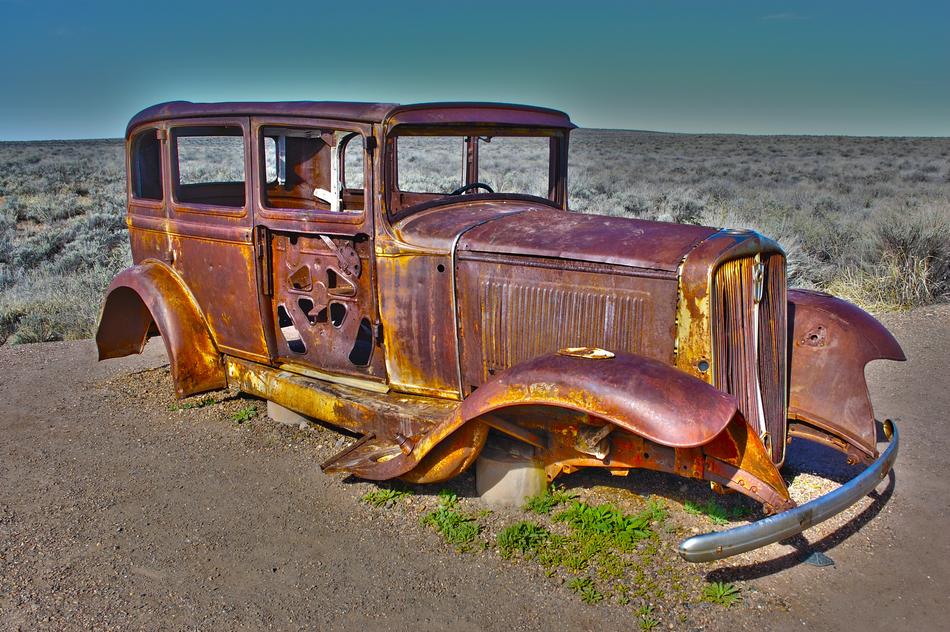 Colorful, old , American car on the sand among the colorful plants