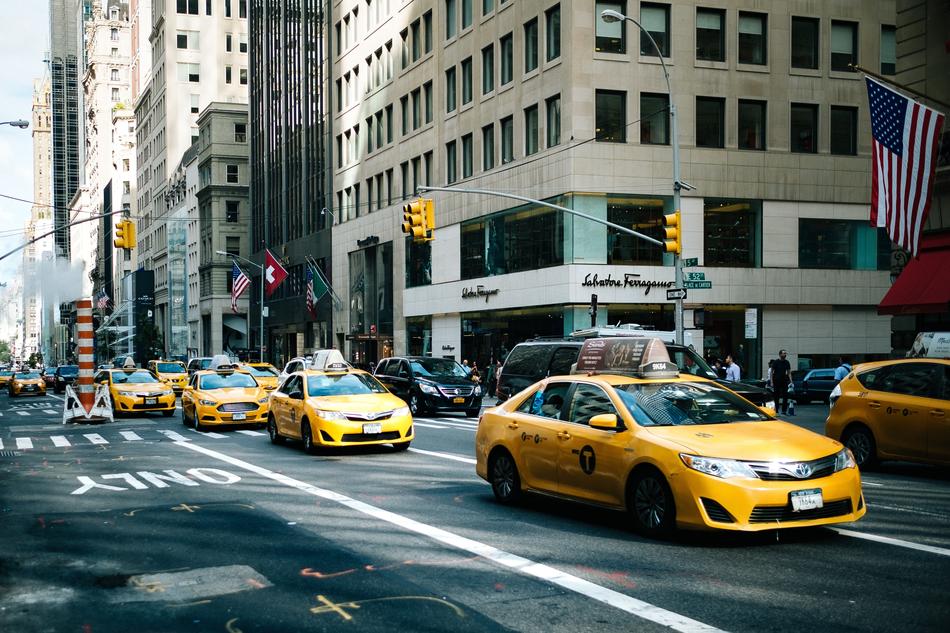 Taxi cars on the road, among the other cars and buildings in the city