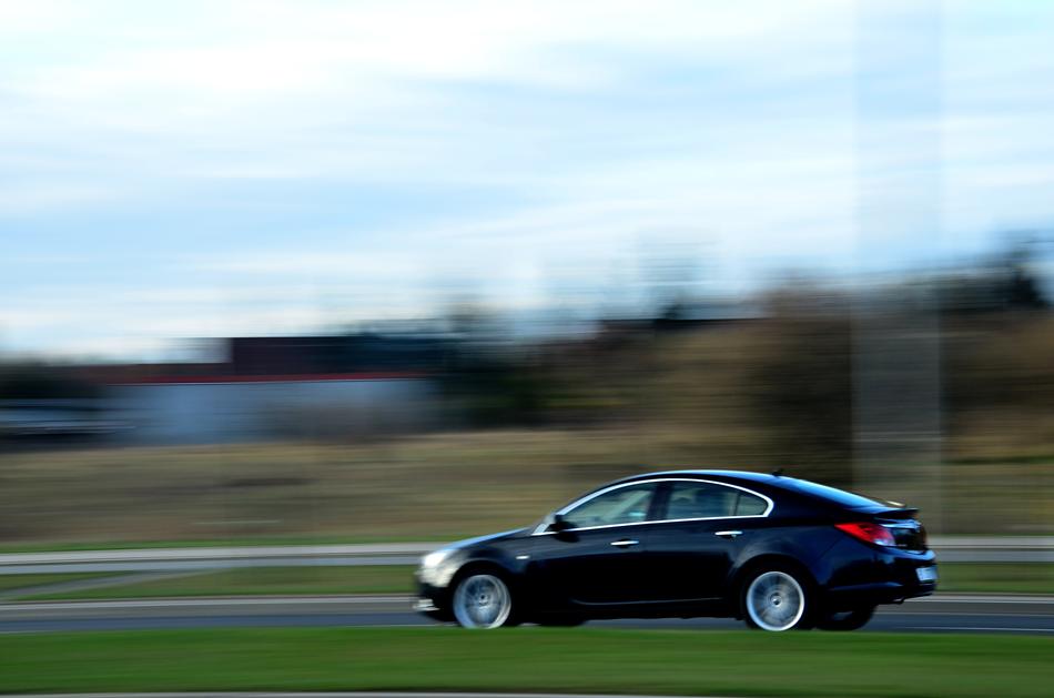 Driving car in motion, on the road, at blurred background with plants