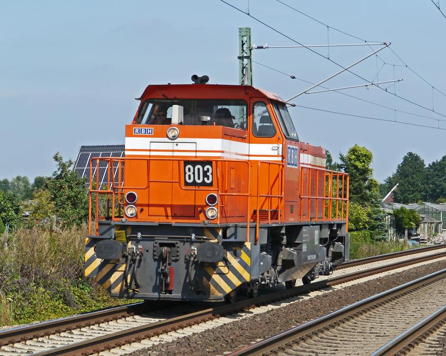 Orange and white diesel locomotive on the railway, among the colorful plants