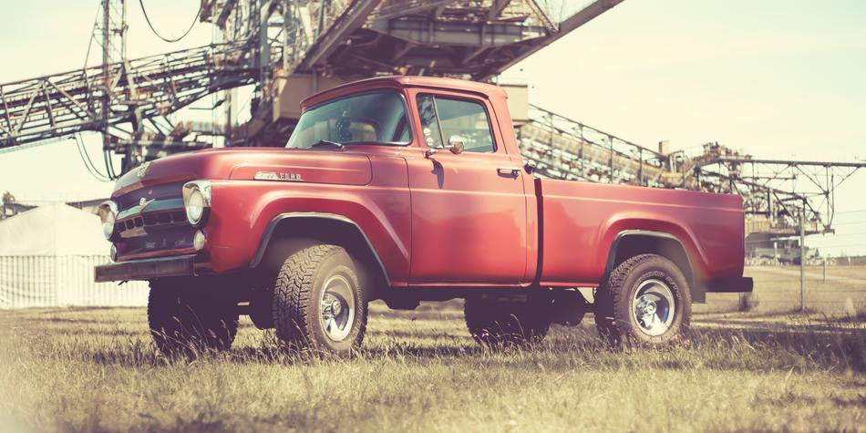 Retro landscape with red Ford pick up on the field, near the construction, in USA