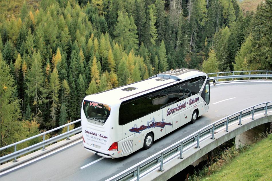 Bus driving on the road, among the beautiful and colorful plants, on the mountains