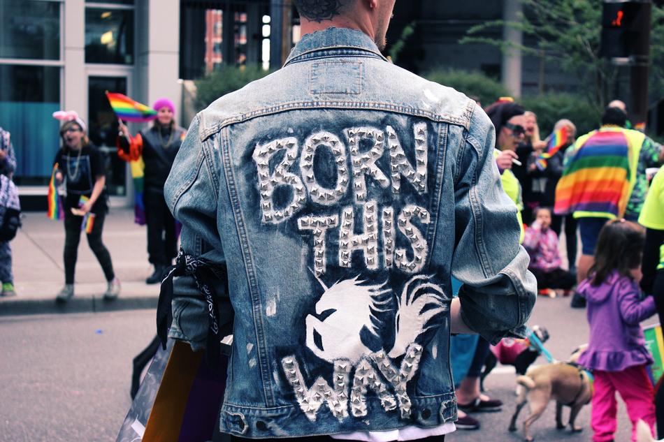 Back view with the man wearing denim jacket with 'Born This Way' sign