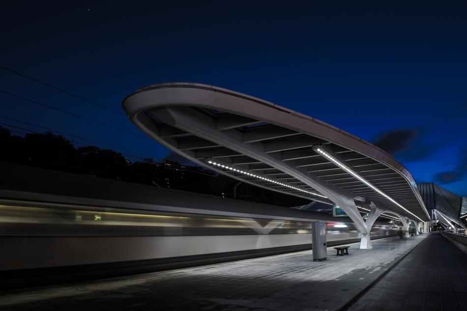 Landscape with the subway station with train in movement, at blurred background, under the beautiful, blue sky in the evening