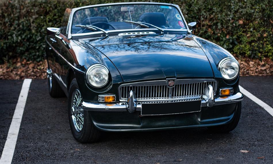 Beautiful, shiny, dark 'MGB' car on the parking lot, near the green plants