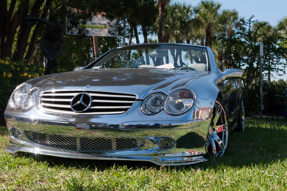 Beautiful, shiny, chrome 'Mercedes' car on the green grass, among the palm trees